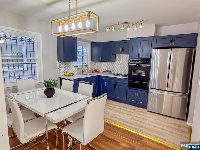 kitchen featuring a sink, light countertops, appliances with stainless steel finishes, blue cabinetry, and a warming drawer