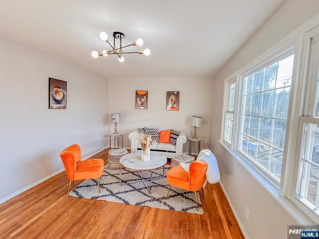 living room featuring an inviting chandelier, baseboards, and wood finished floors