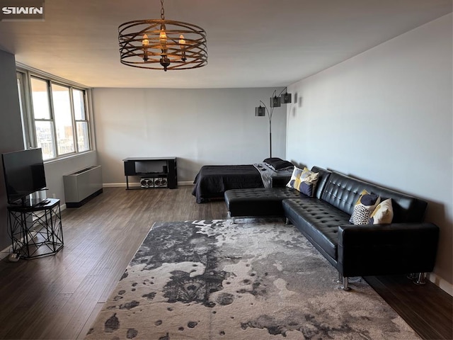 living area featuring radiator heating unit, an inviting chandelier, wood finished floors, and baseboards