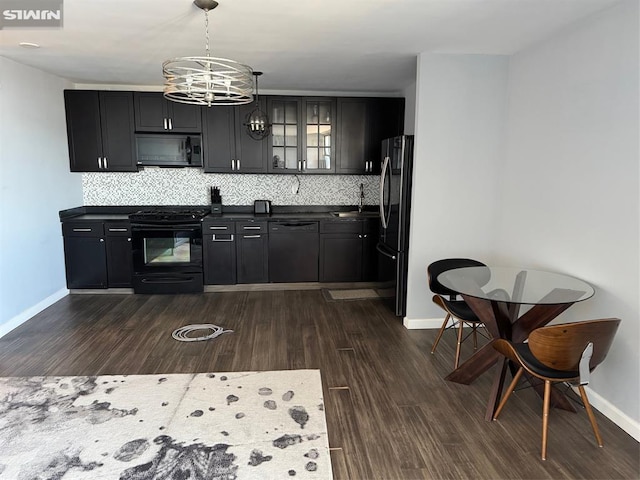 kitchen with dark countertops, black appliances, tasteful backsplash, and dark wood finished floors