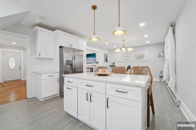 kitchen featuring light countertops, stainless steel refrigerator with ice dispenser, baseboard heating, and white cabinetry