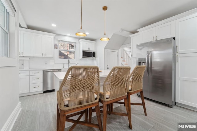 kitchen with decorative light fixtures, stainless steel appliances, recessed lighting, light countertops, and white cabinetry