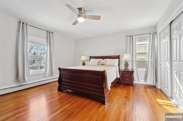 bedroom featuring light wood-type flooring, a baseboard radiator, a closet, and a ceiling fan