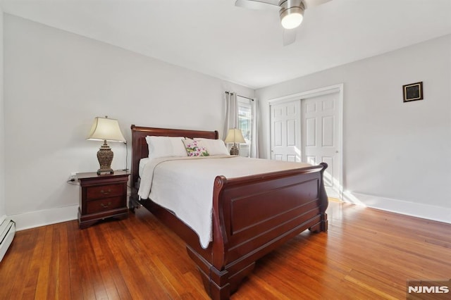 bedroom featuring baseboards, a ceiling fan, wood-type flooring, baseboard heating, and a closet