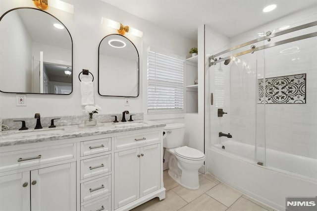 bathroom featuring double vanity, a sink, toilet, and tile patterned floors