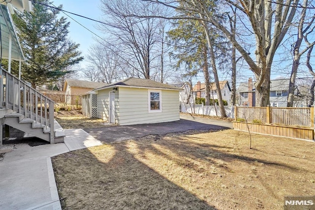 view of yard featuring stairs, an outbuilding, fence, and a patio