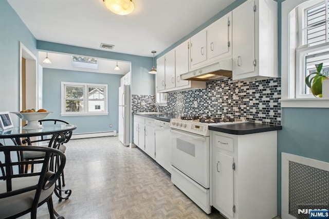 kitchen with white appliances, dark countertops, backsplash, under cabinet range hood, and a sink