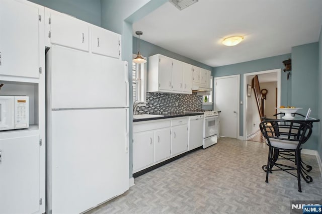 kitchen with white appliances, tasteful backsplash, visible vents, white cabinets, and a sink