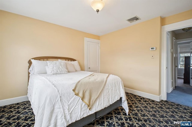 carpeted bedroom with a baseboard heating unit, visible vents, and baseboards