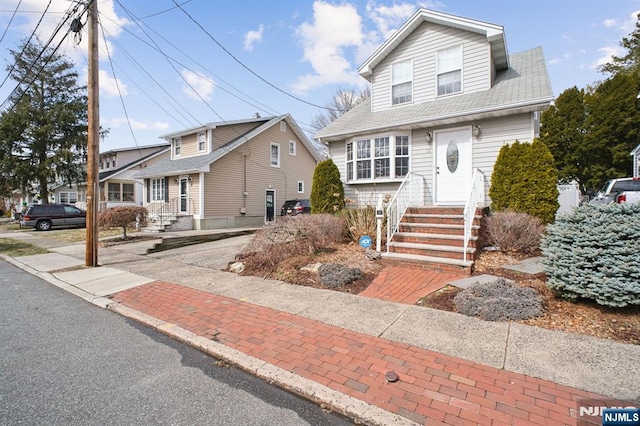 view of front of home with entry steps and a shingled roof