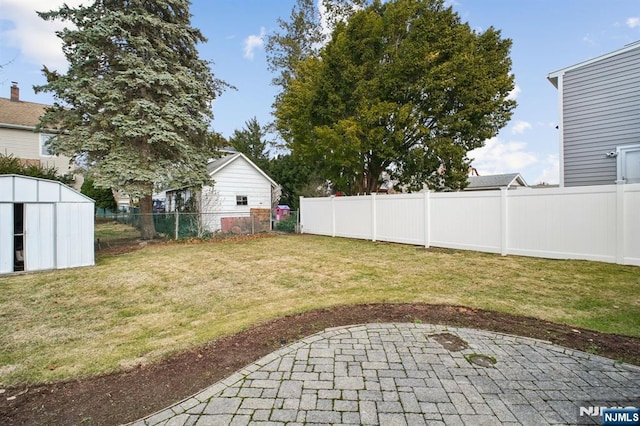 view of yard featuring a patio area, a fenced backyard, a storage unit, and an outbuilding