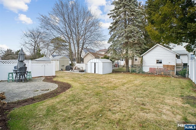 view of yard featuring a patio area, a fenced backyard, an outdoor structure, and a storage shed