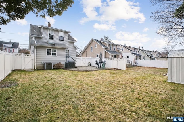 rear view of property featuring a gate, a fenced backyard, a lawn, and central AC unit