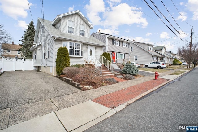 split level home with a residential view, roof with shingles, fence, and entry steps