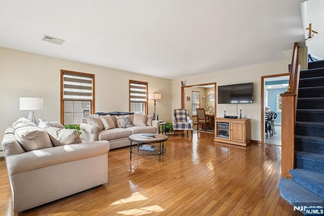 living room with light wood-style floors, visible vents, and stairway