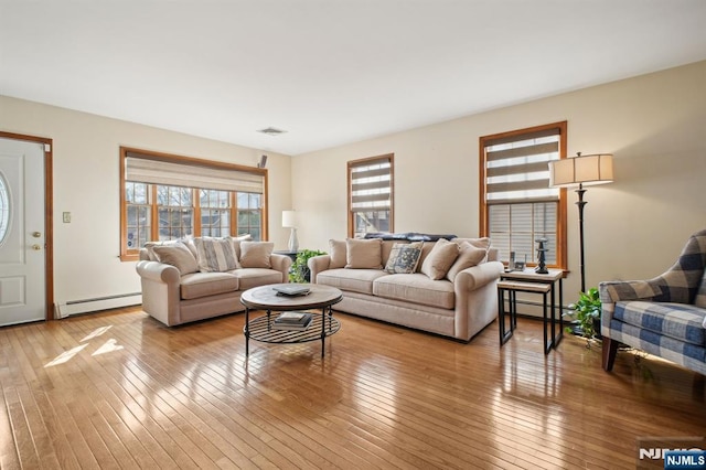 living room with light wood finished floors, visible vents, and a baseboard heating unit