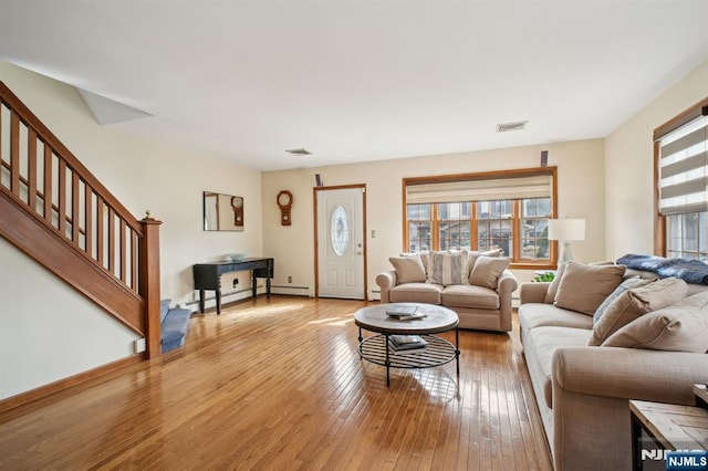 living area with light wood-type flooring, stairway, visible vents, and baseboard heating