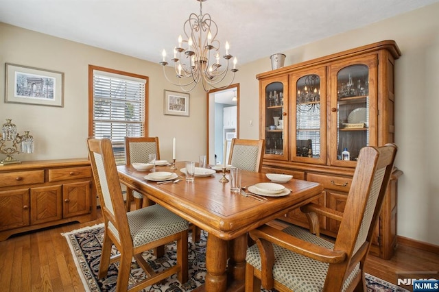 dining space with light wood-type flooring and a notable chandelier