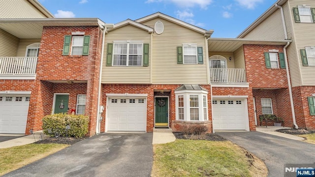 multi unit property featuring driveway, brick siding, and an attached garage