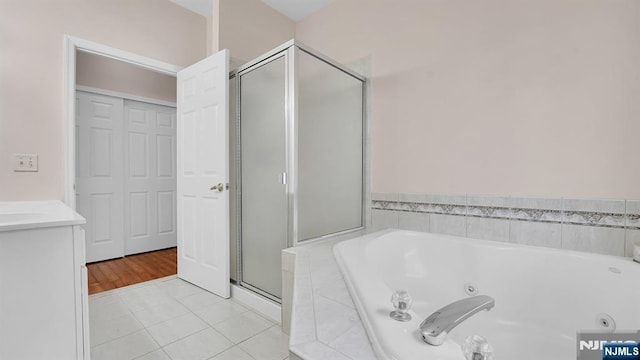 full bath featuring a tub with jets, a stall shower, vanity, and tile patterned floors