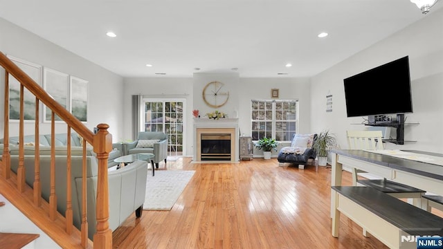 living room with light wood-type flooring, a fireplace with flush hearth, stairway, and recessed lighting