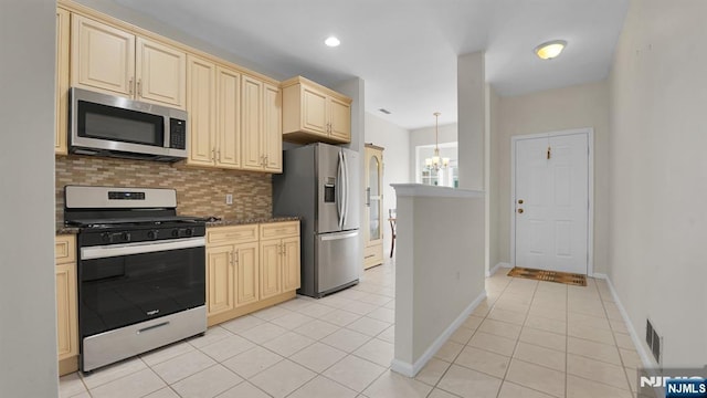 kitchen featuring cream cabinets, light tile patterned flooring, a notable chandelier, stainless steel appliances, and backsplash