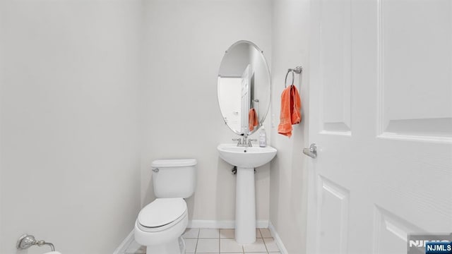 half bath with baseboards, toilet, and tile patterned floors