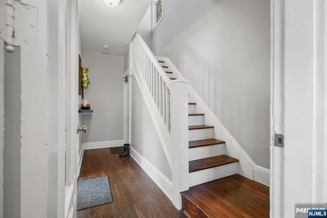 staircase featuring baseboards and wood finished floors