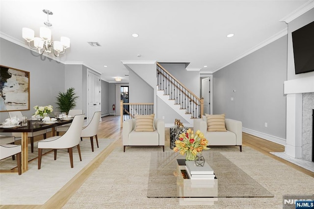 living room with crown molding, a fireplace with flush hearth, wood finished floors, a chandelier, and stairs