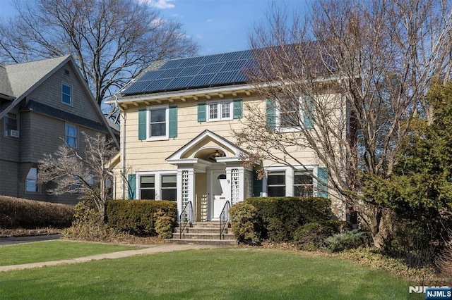 view of front facade with roof mounted solar panels and a front yard