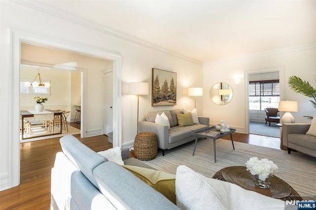 living area featuring a chandelier, crown molding, baseboards, and wood finished floors