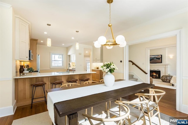 kitchen with a peninsula, a lit fireplace, a sink, and wood finished floors