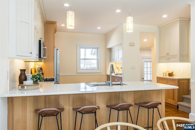 kitchen featuring a peninsula, a wealth of natural light, stainless steel microwave, and a sink