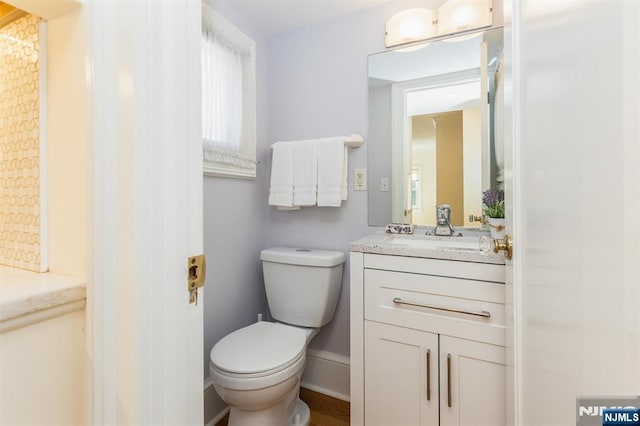 bathroom with baseboards, vanity, and toilet