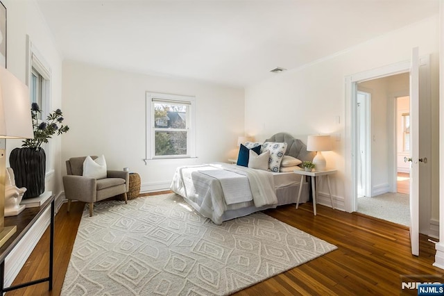 bedroom with wood finished floors, visible vents, and baseboards