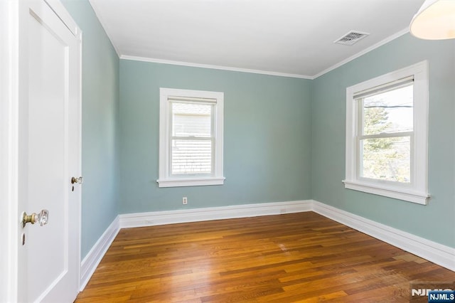 unfurnished room with baseboards, crown molding, visible vents, and wood finished floors