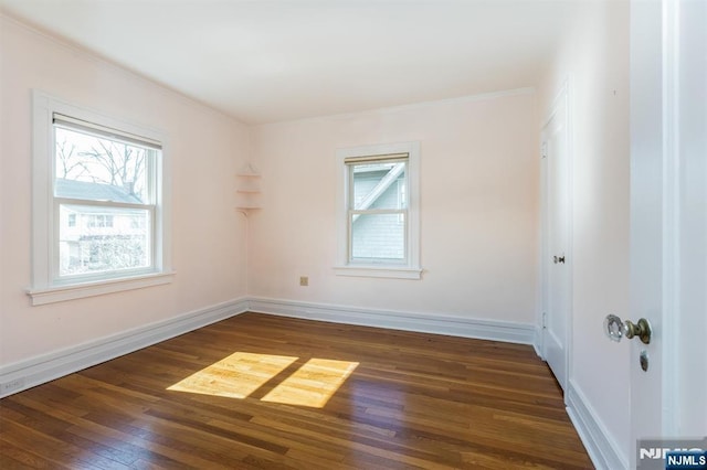 empty room with wood-type flooring, baseboards, and ornamental molding