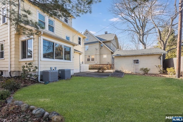 rear view of property featuring central AC, a lawn, and fence