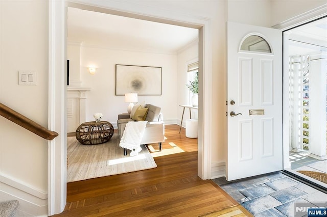 foyer entrance featuring crown molding, stairway, baseboards, and wood finished floors