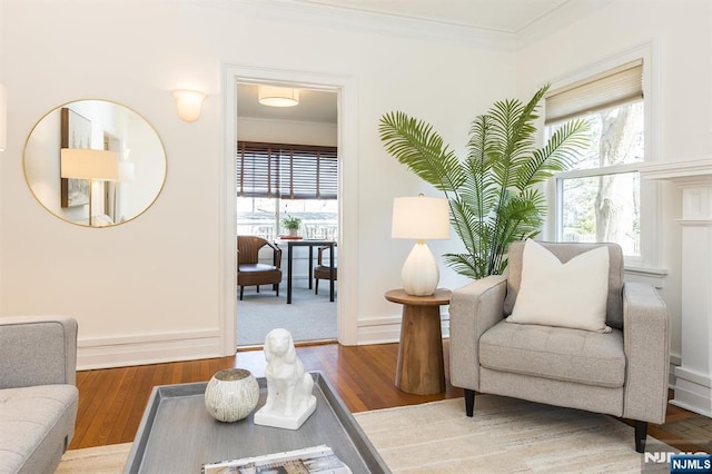 living area featuring plenty of natural light, baseboards, crown molding, and wood finished floors