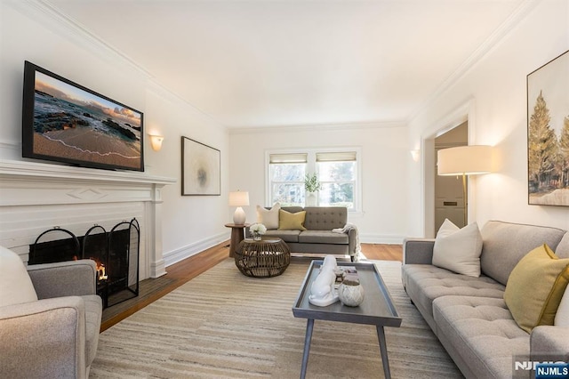 living room with a fireplace with flush hearth, crown molding, baseboards, and wood finished floors