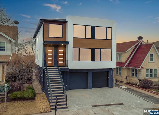 contemporary home with a garage, decorative driveway, and stucco siding