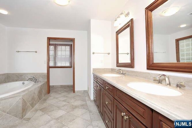 bathroom with a garden tub, a sink, and double vanity