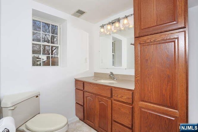 bathroom with toilet, visible vents, and vanity