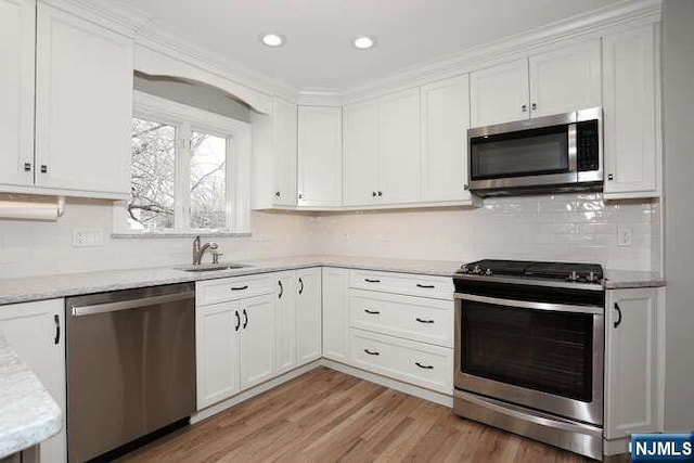 kitchen featuring stainless steel appliances, light wood-type flooring, white cabinets, and a sink