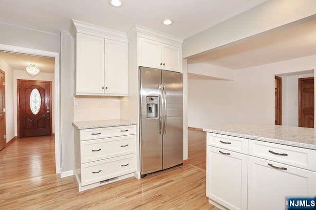 kitchen with stainless steel refrigerator with ice dispenser, recessed lighting, light wood-style flooring, white cabinets, and light stone countertops