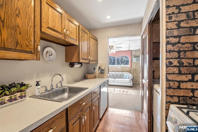 kitchen with brown cabinets, washer and clothes dryer, light countertops, a sink, and dishwasher