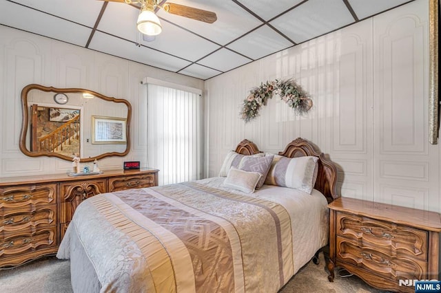 bedroom featuring a ceiling fan, carpet, and a drop ceiling