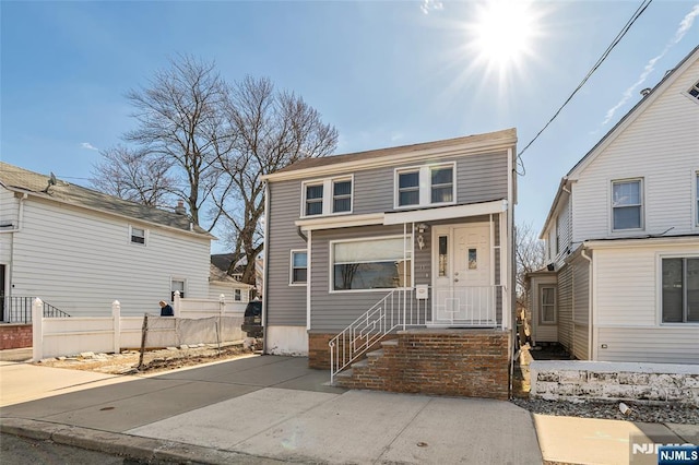 view of front of house featuring concrete driveway and fence