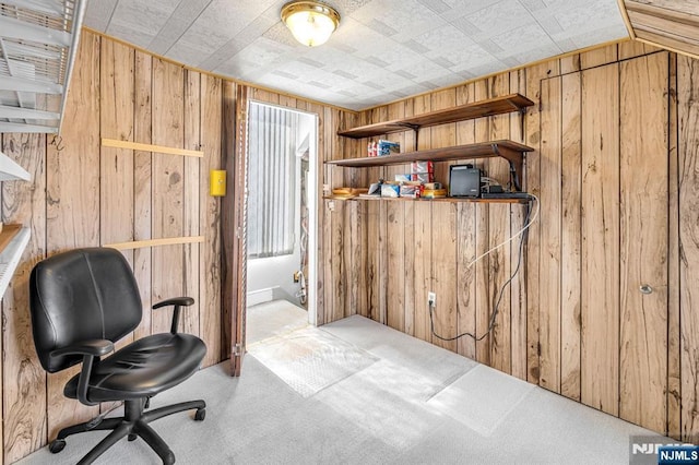 carpeted office space featuring wood walls